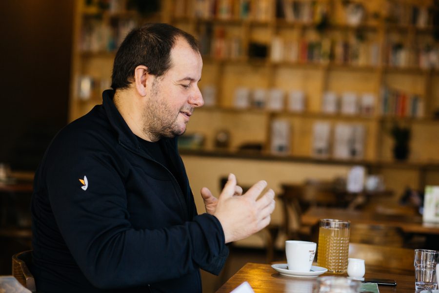 Martin z profilu, gestikulujúc rukami nad šálkou s kávou