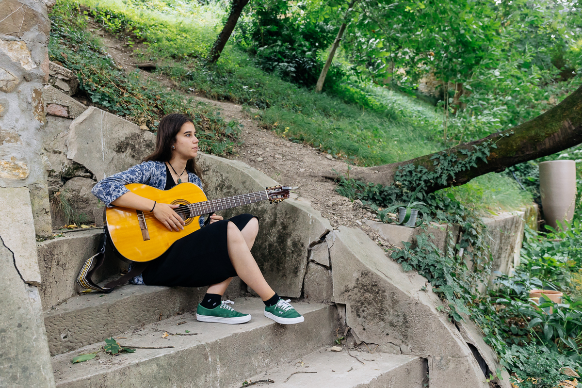 Veronika Kostková sedí na schodoch s gitarou v ruke