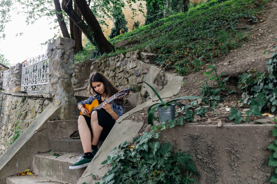 Veronika sedí na schodoch a hrá na gitare